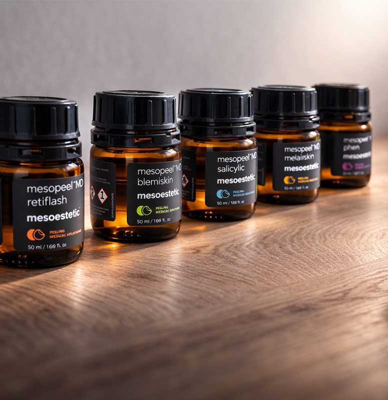 Fünf Mesoestetic Mesopeel MD Flaschen mit verschiedenen Fruchtsäurelösungen auf Holztisch für Hautbehandlung​​​​​​​​​​​​​​​​​​​​​​​​​​​​​​​​​​​​​