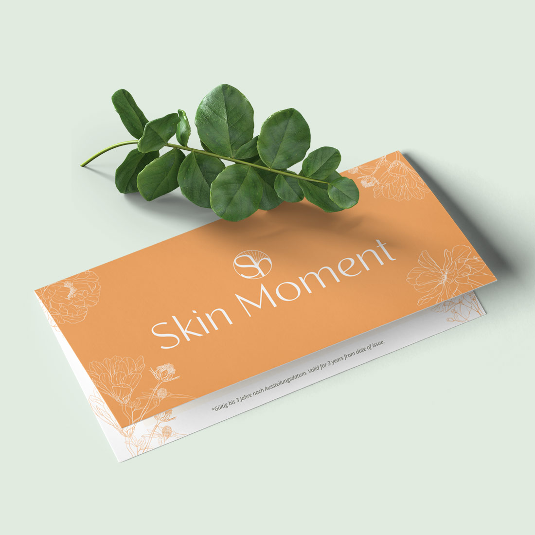 Geschenkgutschein Skin Moment mit floralen Mustern und grünen Blättern auf hellem Untergrund, kosmetisches Geschenk​​​​​​​​​​​​​​​​​​​​​​​​​​​​​​