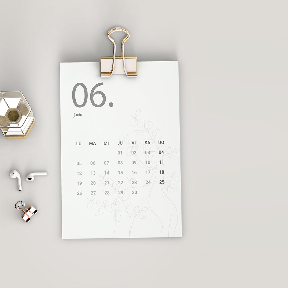 Kalenderblatt für Juni mit goldener Büroklammer, weißen AirPods und dekorativem Kerzenhalter auf hellem Untergrund​​​​​​​​​​​​​​​​​​​​​​​​​​​​​​​